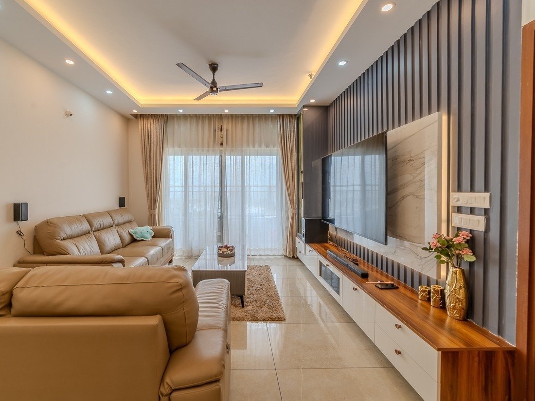 Living room with fluted wood wall panelling behind a floating TV unit and warm cove lighting